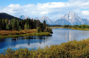 Two people canoeing on river in front of Grand Tetons